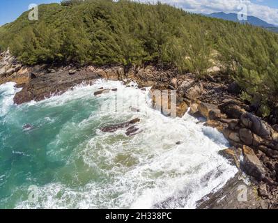 Luftaufnahme mit Wellen, Felsen und Pinien, Praia da Barra, Garopaba, Santa Catarina, Brasilien Stockfoto