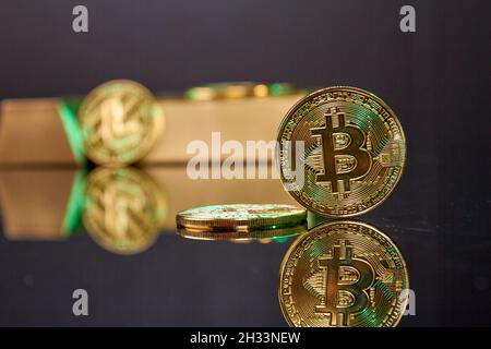 Stehende Bitcoin-Münze auf dem reflektierenden Schreibtisch. Stockfoto