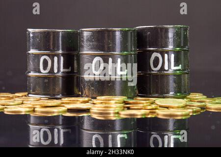 Fässer mit Öl- und Goldmünzen auf dem reflektierenden Schreibtisch. Stockfoto