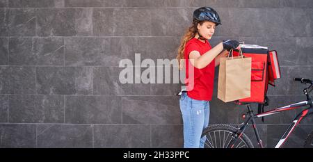 Eine Radfahrerin nimmt die Bestellung aus dem Rucksack Stockfoto
