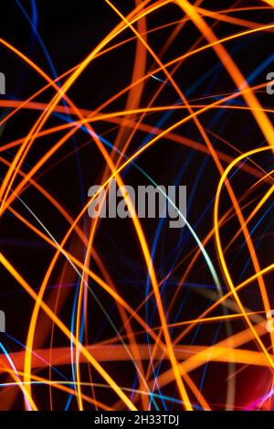 Abstrakter, farbenfroher Hintergrund, orangefarbene und blaue Lichtlinien, die sich durch den gesamten Rahmen schneiden. Stockfoto
