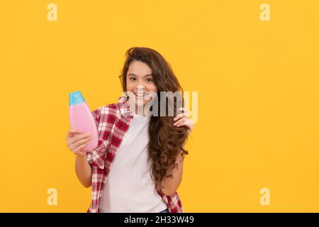 Präsentieren kosmetisches Produkt. Schönheit. Kind verwenden Duschgel. Happy teen Mädchen mit Shampoo-Flasche. Stockfoto