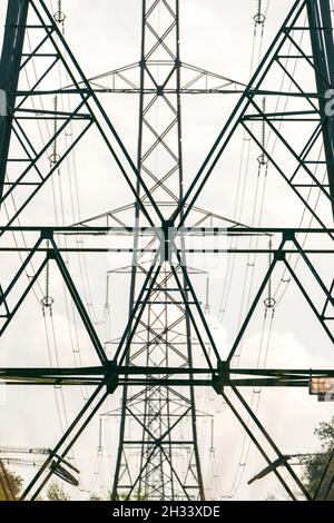 Pylons des united Kingdom National Grid mit Übertragungskabeln über Kopf und Stromleitungen, die durch einen Waldbrandbruch verlaufen. Komprimierte Perspektive. Stockfoto