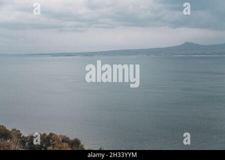 Von der Klippe aus hat man einen herrlichen Blick auf das Meer und die Berge. Schöne Aussicht auf die Bucht. Möwe fliegt im wolkigen Himmel über dem Meer. Schönes Naturkonzept Stockfoto