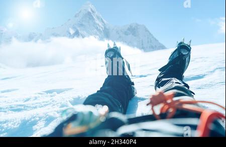 POV schießen eines Höhenbergsteigers die Lags in Steigeisen. Er liegt und ruht auf Schnee-Eis-Feld mit Ama Dablam (6812m) Gipfel mit c bedeckt Stockfoto