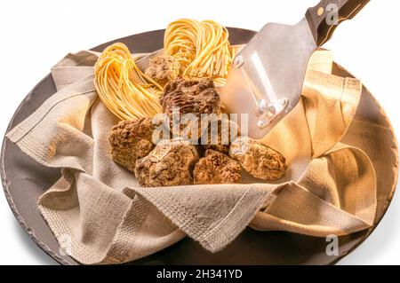 Alba weiße Trüffel in Serviette mit rohem Ei Tagliolini und Inox Stahl Trüffel Slicer in Balck Schieferplatte isoliert auf weißem Hintergrund Stockfoto