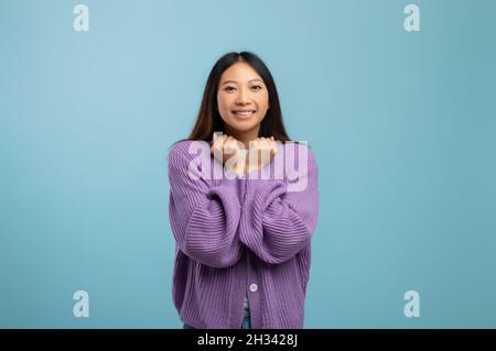 Omm. Überfröhliche und fröhliche asiatische Dame lächelt und schaut die Kamera an, drückt positive Emotionen aus, steht auf blauem Hintergrund, Studioaufnahme, Banner Stockfoto
