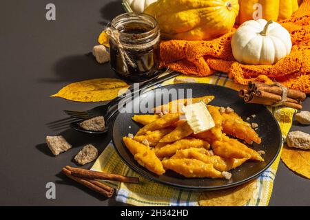 Faule Kürbisknödel, Gnocchi mit Butter und braunem Zucker. Warmes Herbstgericht, süße gesunde Lebensmittel. Schwarzer Stein Beton Hintergrund, trendy hartes Licht, Stockfoto