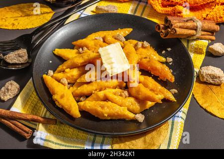 Faule Kürbisknödel, Gnocchi mit Butter und braunem Zucker. Warmes Herbstgericht, süße gesunde Lebensmittel. Schwarzer Stein Beton Hintergrund, trendy hartes Licht, Stockfoto