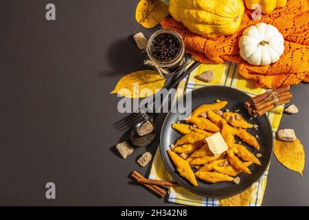 Faule Kürbisknödel, Gnocchi mit Butter und braunem Zucker. Warmes Herbstgericht, süße gesunde Lebensmittel. Schwarzer Stein Beton Hintergrund, trendy hartes Licht, Stockfoto