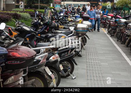 Reihen von Motorrollern, die auf der Straße im Nanshi District oder in der Altstadt von Shanghai, China, geparkt sind. Stockfoto