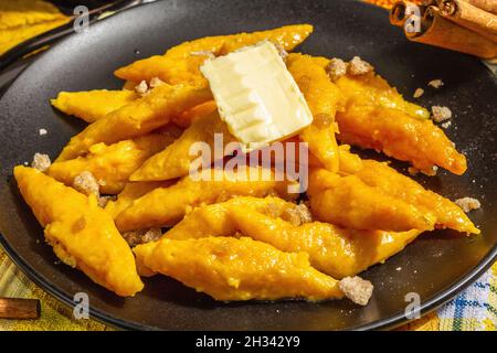 Faule Kürbisknödel, Gnocchi mit Butter und braunem Zucker. Warmes Herbstgericht, süße gesunde Lebensmittel. Schwarzer Stein Beton Hintergrund, trendy hartes Licht, Stockfoto