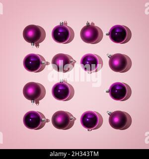 Funkelnde helle weihnachtskugeln in violetter Farbe liegen in Form eines Quadrats auf einem rosa Hintergrund, weihnachtsfest-Konzept, flaches Lay, Stockfoto