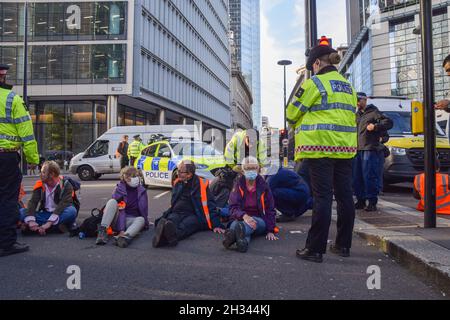 London, Großbritannien. Oktober 2021. Beleidigung Großbritanniens Demonstranten klebten sich an die Straße und blockierten die Wormwood Street und Bishopsgate in der Nähe der Liverpool Street Station. Die Demonstranten fordern, dass die Regierung bis 2025 alle sozialen Wohnungsbauten isoliert und die Verantwortung dafür übernimmt, dass alle Häuser im Vereinigten Königreich bis 2030 energieeffizienter sind, als Teil der umfassenderen Ziele für den Klimawandel und die Dekarbonisierung. Stockfoto