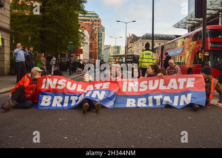 London, Großbritannien. Oktober 2021. Beleidigung Großbritanniens Demonstranten klebten sich an die Straße und blockierten die Wormwood Street und Bishopsgate in der Nähe der Liverpool Street Station. Die Demonstranten fordern, dass die Regierung bis 2025 alle sozialen Wohnungsbauten isoliert und die Verantwortung dafür übernimmt, dass alle Häuser im Vereinigten Königreich bis 2030 energieeffizienter sind, als Teil der umfassenderen Ziele für den Klimawandel und die Dekarbonisierung. Stockfoto