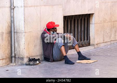 Huelva, Spanien - 24. Oktober 2021: Schwarzer Obdachloser bettelt auf der Straße um Geld Stockfoto