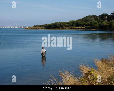 Mann, der in Christchurch Harbour, Dorset, Großbritannien angeln will Stockfoto