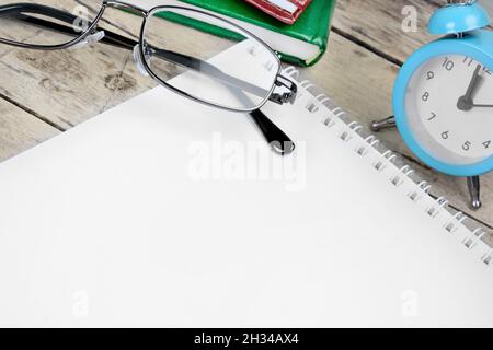 Wecker, Bleistift und Notizbuch auf Holzschreibtisch Stockfoto