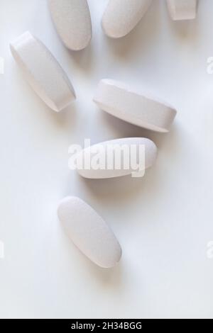 Weiße oder hellgraue lange Vitamine oder Pillen auf weißem Hintergrund, Makro, Nahaufnahme, Kopierraum, flach. Nahrungsergänzungsmittel Konzept, Gesundheit, Vitamine Stockfoto