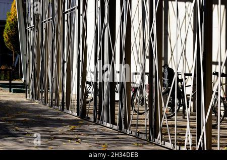 Moderner pulverbeschichteter Aluminiumzaun. Grauer Gehsteig aus Stein. Straßenlandschaft im Hintergrund. Urbane Szene. Fahrradspeichergehäuse. privatsphärenbildschirm. Stockfoto