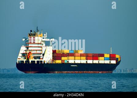 Farbige Transportbehälter, die den Hafen mit dem Boot verlassen, Mangel an Waren zu weihnachten Stockfoto