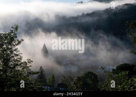 Am frühen Morgen bedeckt der Nebel das Dorf Saint-Étienne-de-Baïgorry, von der Landstraße aus gesehen, die zum Col d'Izpégi, Frankreich, führt Stockfoto