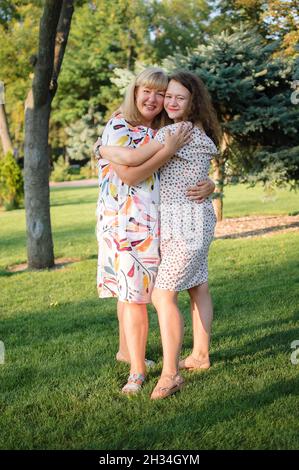 Weibliche Porträt einer schönen plus size blonde, blauäugige Mutter und Tochter im Park im Sommer. Familientag, Happy People Konzept Stockfoto