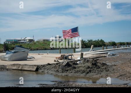 Grand Isle, Vereinigte Staaten von Amerika. 16. Oktober 2021. Nach dem Hurrikan Ida, Wochen nach dem verheerenden Sturm der Kategorie 4, der die Region am 16. Oktober 2021 in Grand Isle, Louisiana heimsuchte, flattert eine amerikanische Flagge auf einem zerstörten Fischerdock. Quelle: Patsy Lynch/FEMA/Alamy Live News Stockfoto