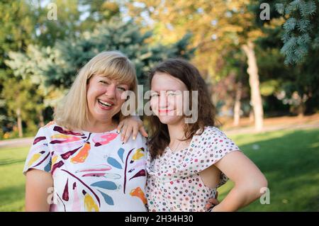 Weibliche Porträt einer schönen plus size blonde, blauäugige Mutter und Tochter im Park im Sommer. Familientag, Happy People Konzept Stockfoto