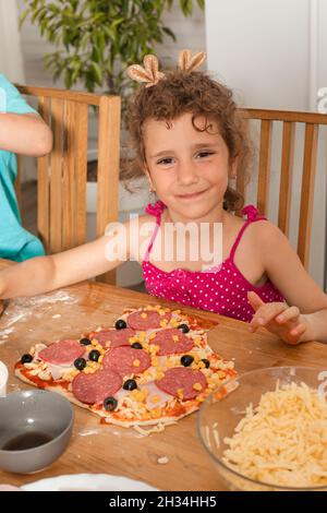 Das kleine Mädchen kochte ihre Lieblingspizza Stockfoto