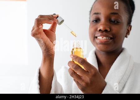 Flasche Serum mit Tropfen, der von der Pipette fällt Stockfoto