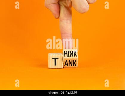 Symbol für Denkfabrik. Geschäftsmann dreht einen Holzwürfel und ändert das Wort „Tank“ in „denken“ oder umgekehrt. Schöner orangefarbener Tisch, orangefarbener Hintergrund, CO Stockfoto