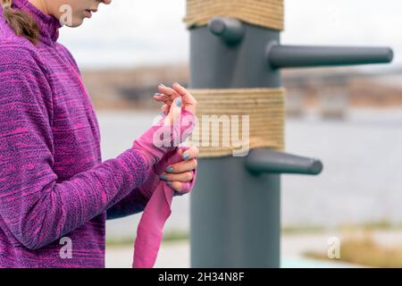 Mädchen wickelte ein Handgelenk um ihre Hand, bevor sie im Freien gegen den traditionellen Trainingsdummy trainierten Stockfoto