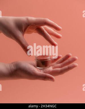 Hausgemachter Lippenbalsam mit weiblichen Händen über rosa Stockfoto