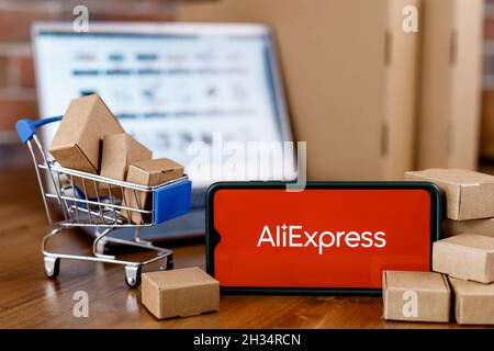 AliExpress ist ein chinesischer Online-Einzelhandel. Smartphone mit AliExpress-Logo auf dem Bildschirm, dem Einkaufswagen und dem Laptop. Stockfoto