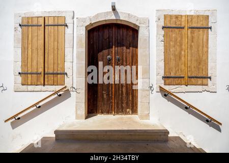 Eingang zu einem alten Gebäude mit einer geschlossenen Holztür und hölzernen Fensterläden Stockfoto