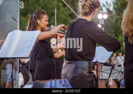 Schöne Geigerin, die im Orchester auf der Straße spielt Stockfoto