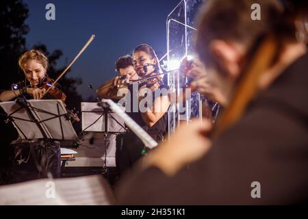 Geigenspieler spielen im Orchester bei einem nächtlichen Konzert im Freien Stockfoto