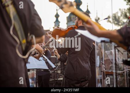 Männlicher Musiker, der im Freien Geige im Orchester spielt Stockfoto