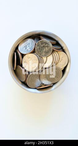 Sortierte Auswahl an aktuellen Verwendung American Quarter Dollar in einem Chrom-Cup auf weißem Hintergrund; U.S. Quarters; Münzen, Währung, Geld. Stockfoto