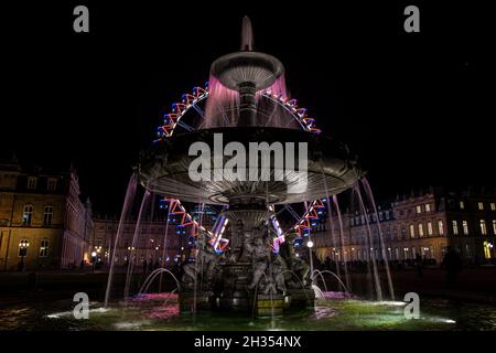 STUTTGART, DEUTSCHLAND - 24. Okt 2021: Brunnen auf dem Stuttgarter Schlossplatz, der nachts mit einem Riesenrad im Hintergrund eingefangen wurde Stockfoto