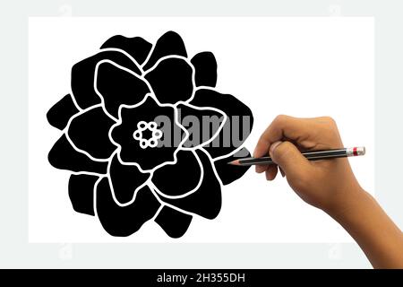 Die Hand des Kindes ist bereit, mit einem schwarzen Bleistift eine schwarze Blume zu zeichnen. Isoliert auf weißem Tischhintergrund. Stockfoto