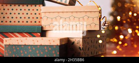 Die Weihnachts-Boxen stehen übereinander neben dem Weihnachtsbaum Stockfoto