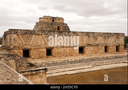 Ostgebäude des Nunnery Quadrangle mit der Pyramide des Magiers, die im Hintergrund bei den Maya-Ruinen von Uxmal, Yucatan, Mexiko, aufsteigt Stockfoto