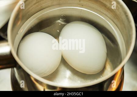 Hühnereier werden in Kochtöpfen auf einem Gasherd gekocht. Stockfoto
