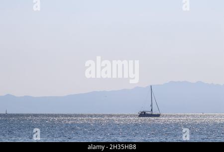 Blaue Meereswellen funkeln in der Sonne und eine Yacht. Sommerferien Konzept Stockfoto