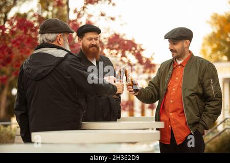 Gruppe von Männern, Freunden, Nachbarn verbringen Zeit zusammen im Freien an warmen Herbsttag. Bier trinken Stockfoto