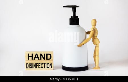 Händedesinfektion, Text ist auf Holzklötze geschrieben.Holzpuppe mit Alkoholspray zur Händedesinfektion. Stockfoto