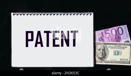 Das Wort Patent ist auf einem Notizbuch und einem schwarzen Hintergrund mit Dollar- und Euro-Scheinen geschrieben Stockfoto