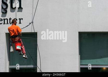 Bukarest, Rumänien, 3. Juni 2009: Der professionelle alpinistische Fensterputzer von Utilitary wäscht die Fassade eines Bürogebäudes, hängend an einem Seil. Stockfoto